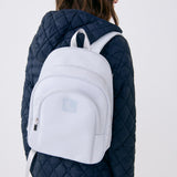 Lolë Chelsea backpack in pale grey, worn on both shoulders from behind, front zip pocket and logo facing the camera