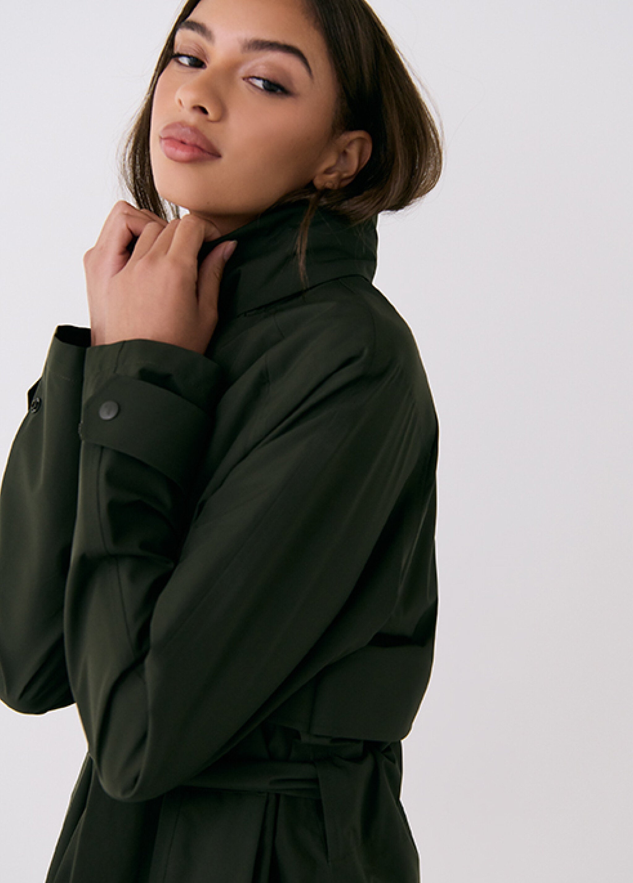 Lolë Alizé rain trench coat in dark olive, close side view of the funnel collar and buttoned cuff tab