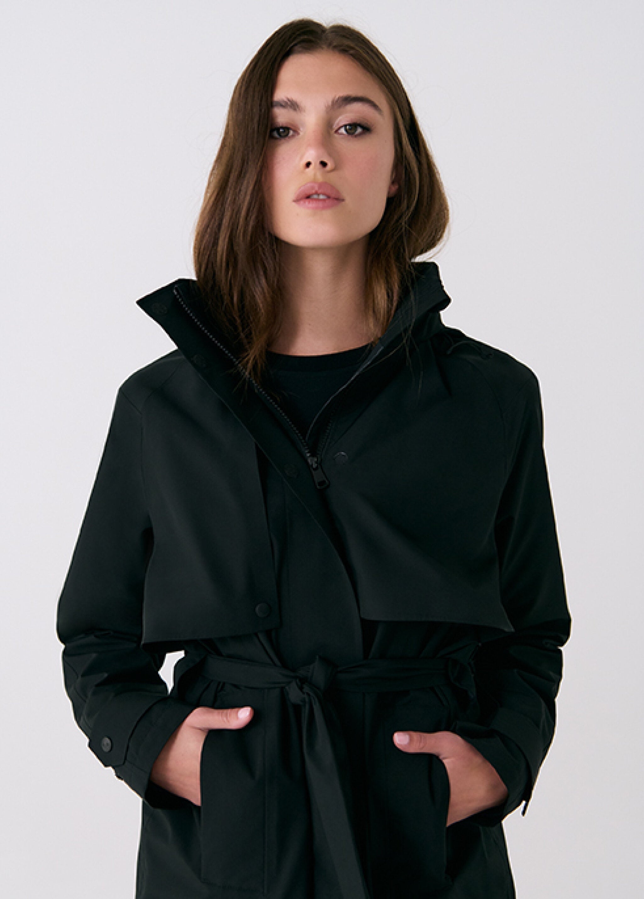 Lolë Alizé rain trench coat in black, close front view of the zip, snap storm flap and tie belt