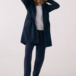 Lolë Piper 2.0 rain jacket in navy, full-length front view worn open over a grey top, hood down and drawcord waist