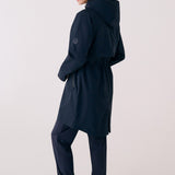 Lolë Piper 2.0 rain jacket in navy, back view showing the hood, back yoke button and gathered drawcord waist