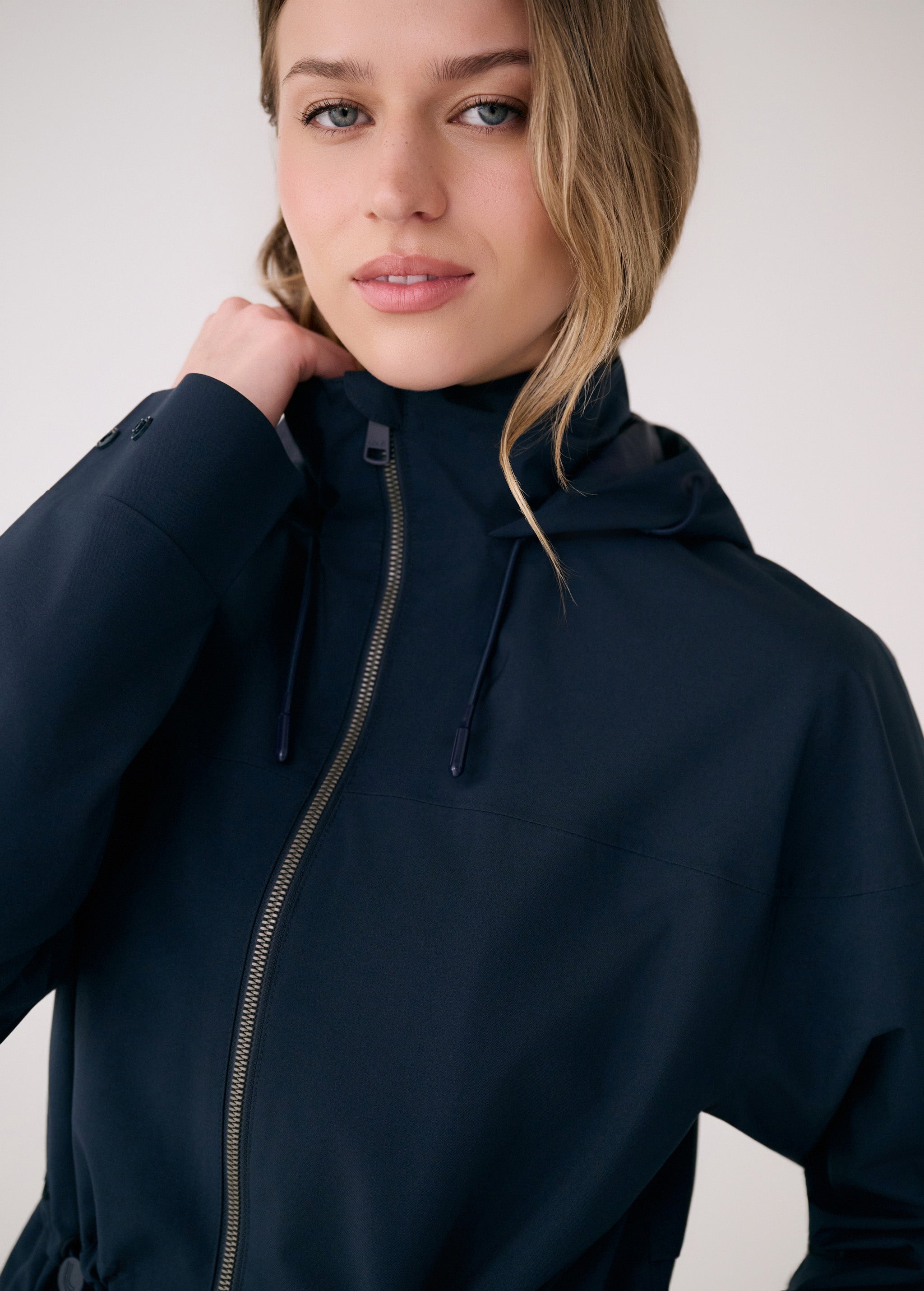 Lolë Piper 2.0 rain jacket in navy, close view of the two-way front zip and drawcord toggles at the neck