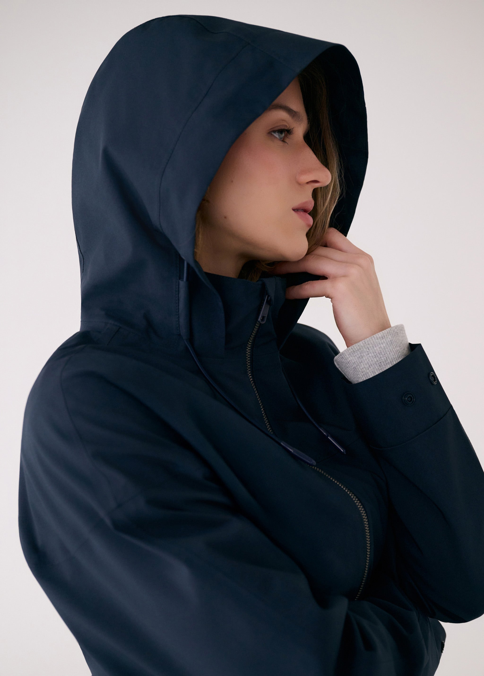 Lolë Piper 2.0 rain jacket in navy, hood-up close-up showing the funnel neck and buttoned cuff