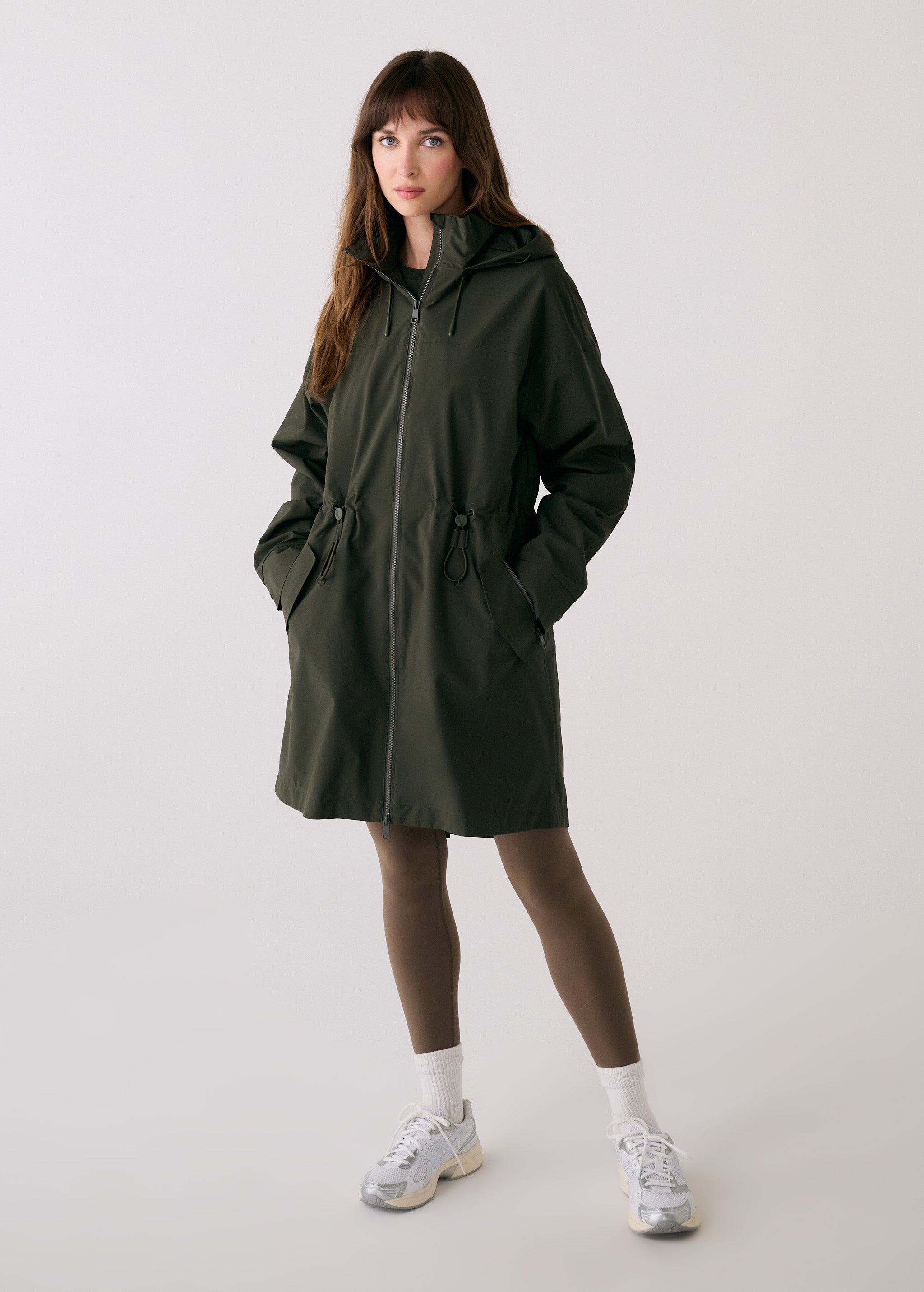 Lolë Piper 2.0 rain jacket in olive green, full-length front view zipped up with hood and drawcord waist