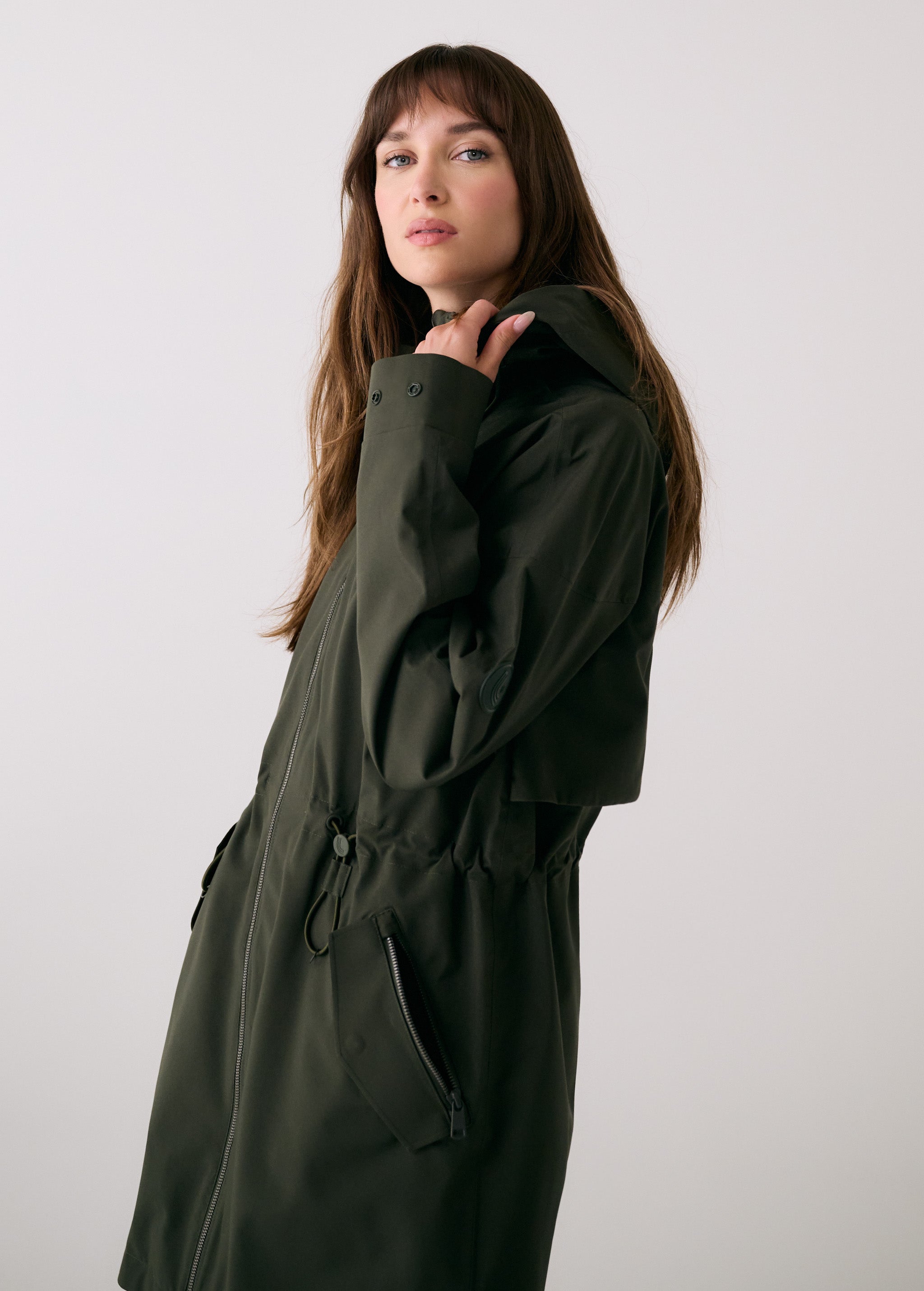Lolë Piper 2.0 rain jacket in olive green, side view showing the drawcord waist, zip pocket and cuff