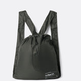 Lolë Piper 2.0 rain jacket in olive green, folded flat into its matching drawstring backpack pouch