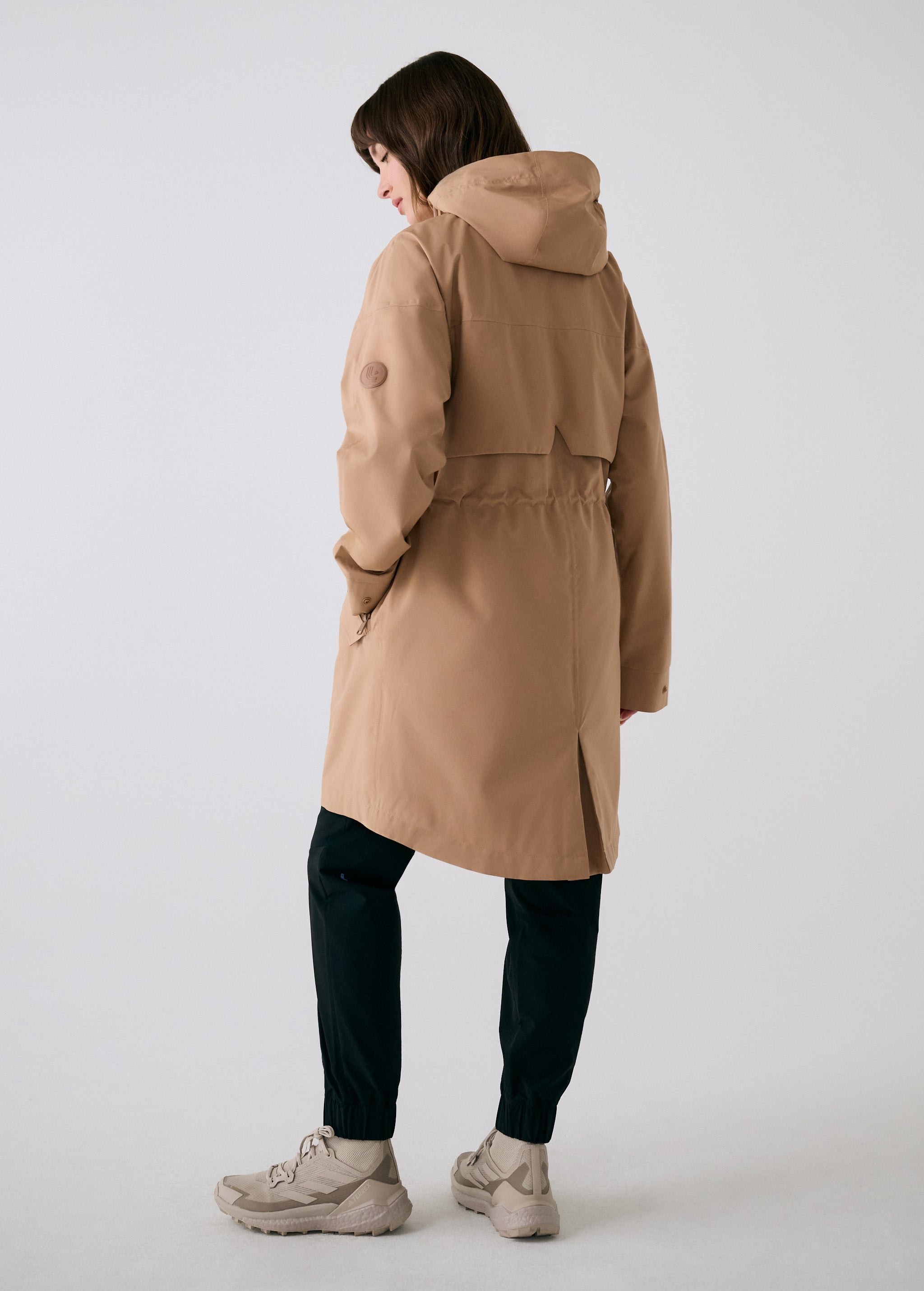 Lolë Piper 2.0 rain jacket in camel, rear view with the hood, back yoke and drawcord-gathered waist