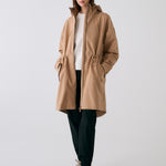 Lolë Piper 2.0 rain jacket in camel, full-length front view worn open over a white top, full-zip and hood