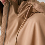 Lolë Piper 2.0 rain jacket in camel, close-up of the collar, front zip and branded hood drawcord toggle