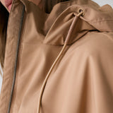 Lolë Piper 2.0 rain jacket in camel, close-up of the collar, front zip and branded hood drawcord toggle