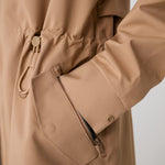 Lolë Piper 2.0 rain jacket in camel, close view of the drawcord waist toggle, flap pocket and cuff snap