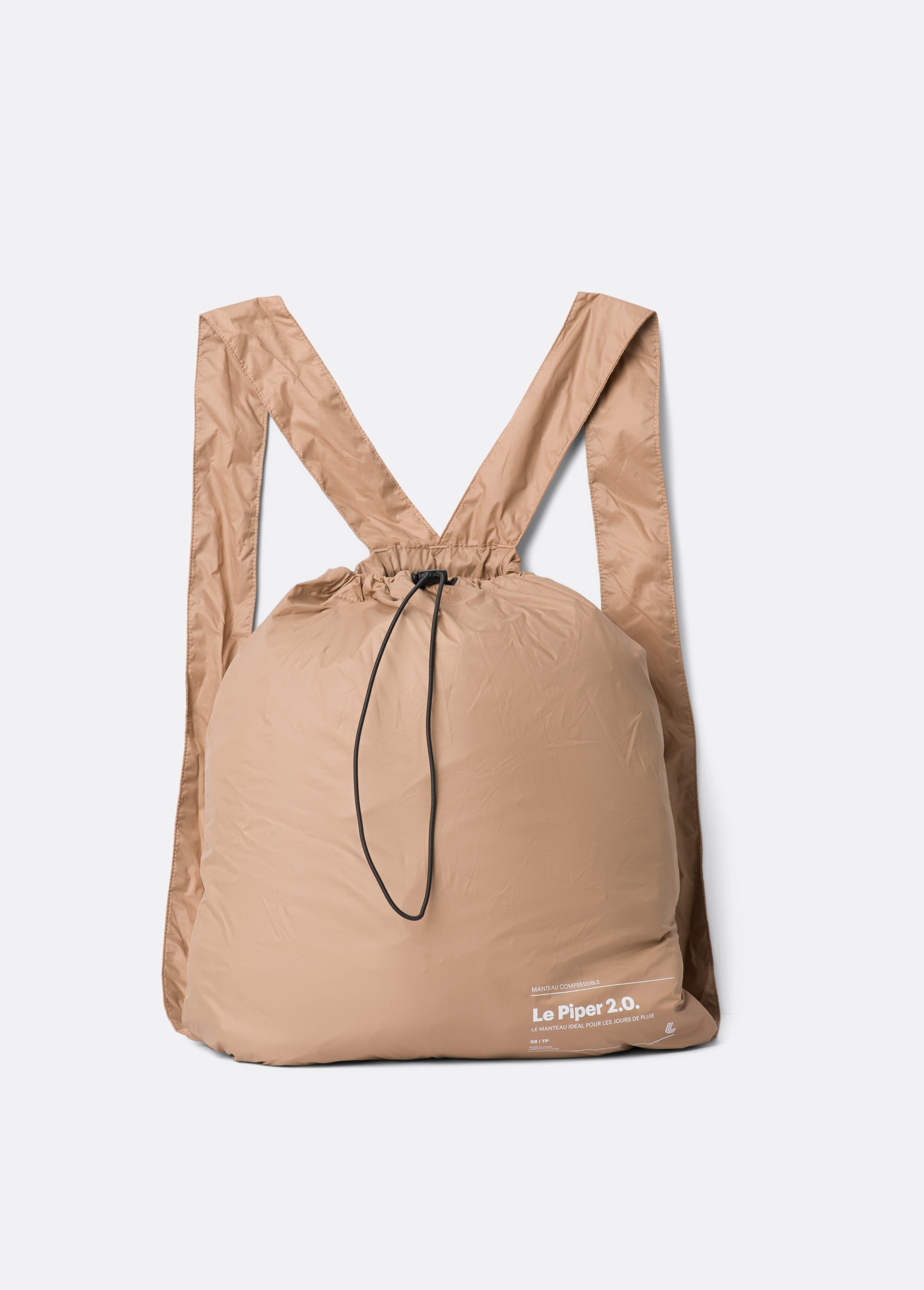 Lolë Piper 2.0 rain jacket in camel, packed flat into its matching drawstring backpack pouch