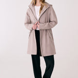 Lolë Piper 2.0 rain jacket in taupe, worn open over a white tee, full front view with hood and drawcord waist