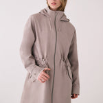 Lolë Piper 2.0 rain jacket in taupe, front view zipped up showing the hood, two-way zip and drawcord waist