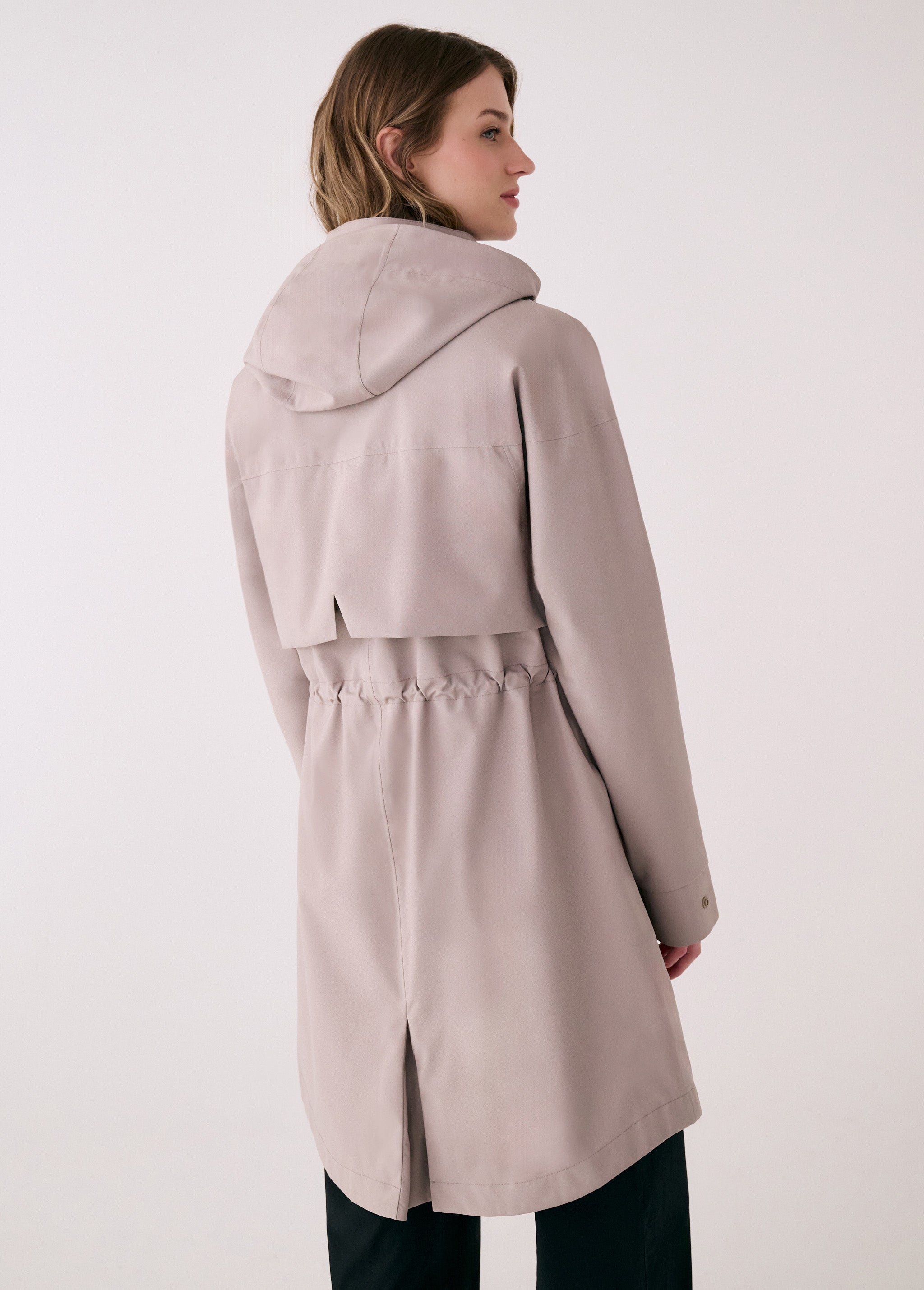 Lolë Piper 2.0 rain jacket in taupe, back view with hood down showing the drawcord waist and centre back vent