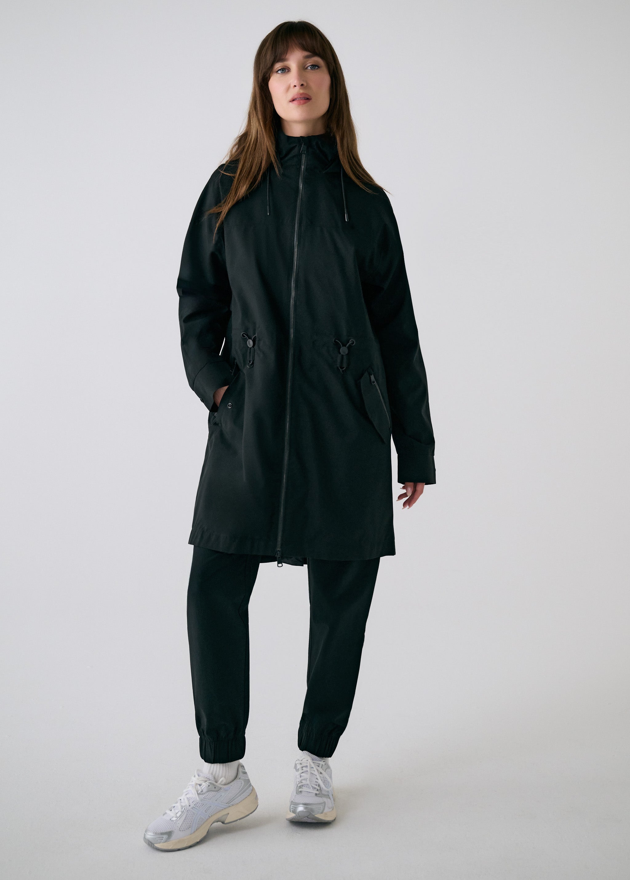 Lolë Piper 2.0 rain jacket in black, full front view zipped up with hood, drawcord waist toggles and hip pockets