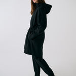 Lolë Piper 2.0 rain jacket in black, full side profile with hood down showing the mid-thigh length