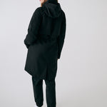 Lolë Piper 2.0 rain jacket in black, rear view with hood down showing the gathered waist and back vent