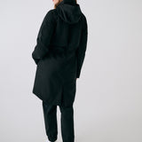 Lolë Piper 2.0 rain jacket in black, rear view with hood down showing the gathered waist and back vent