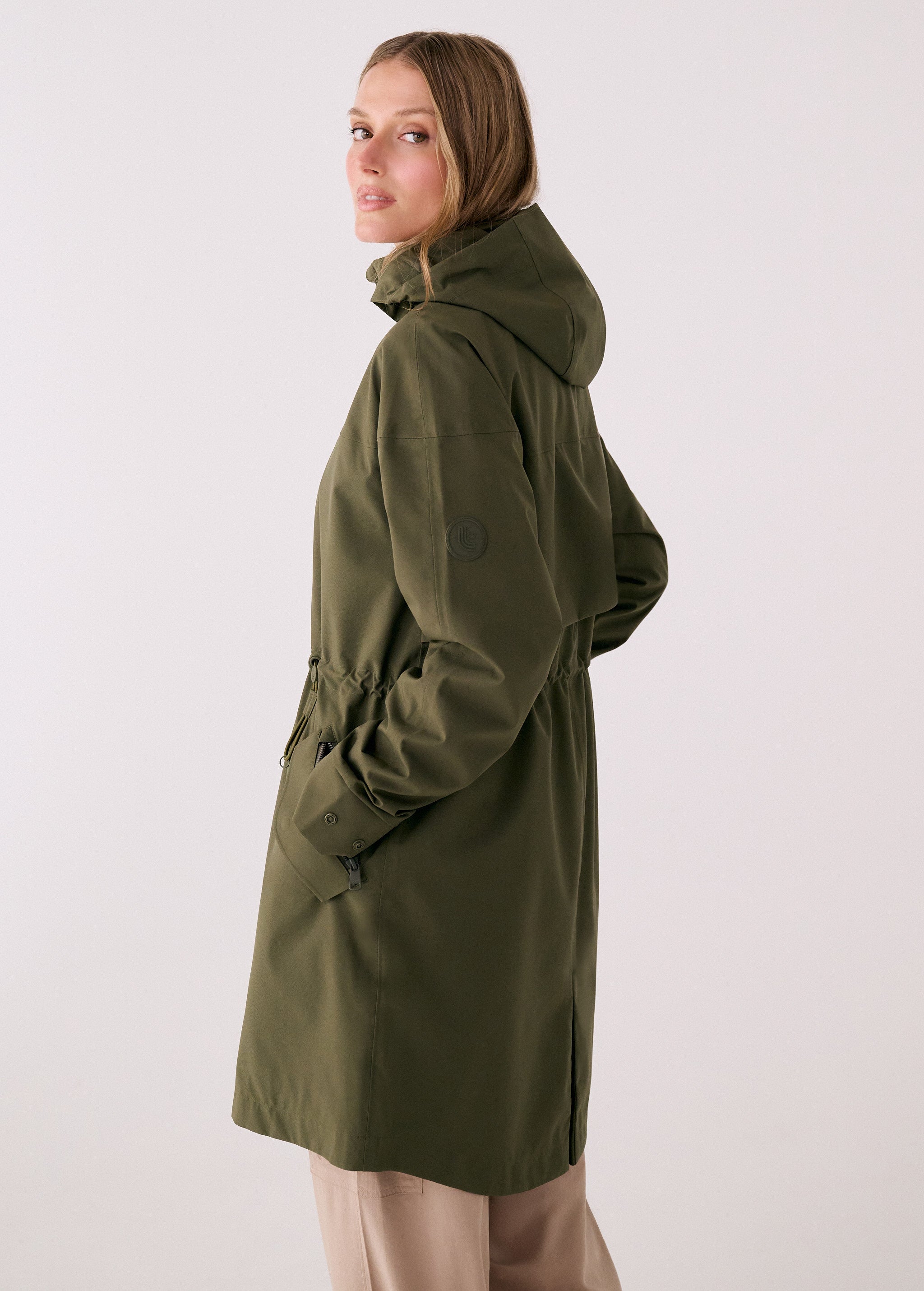 Lolë Piper 2.0 rain jacket in olive green, side view showing the hood, sleeve logo and side hem vent