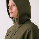 Lolë Piper 2.0 rain jacket in olive green, close-up with the hood up and front zip drawn to the chin