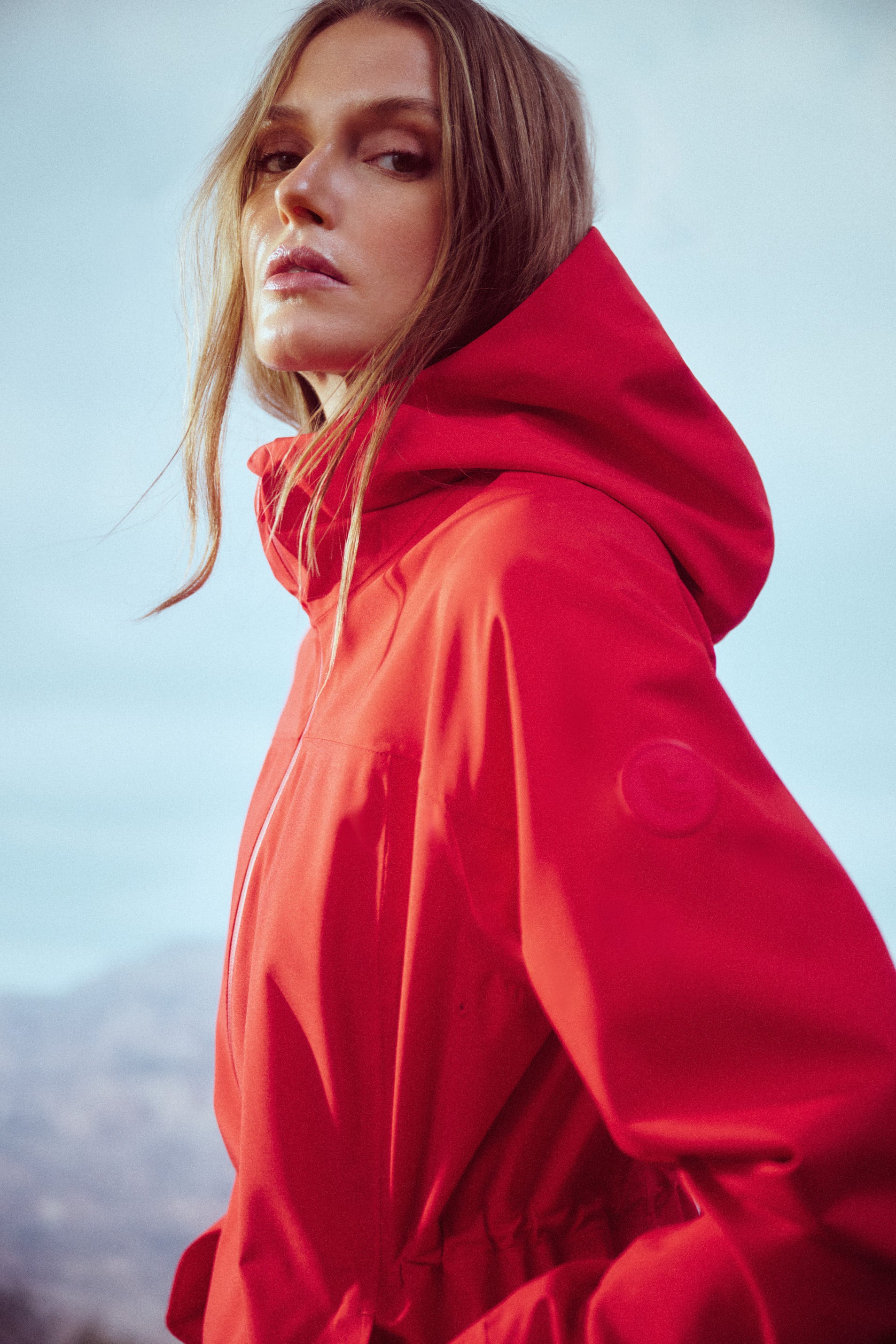 Lolë Element Long Rain Jacket in Poppy red — this longline jacket keeps water out while keeping your look sharp