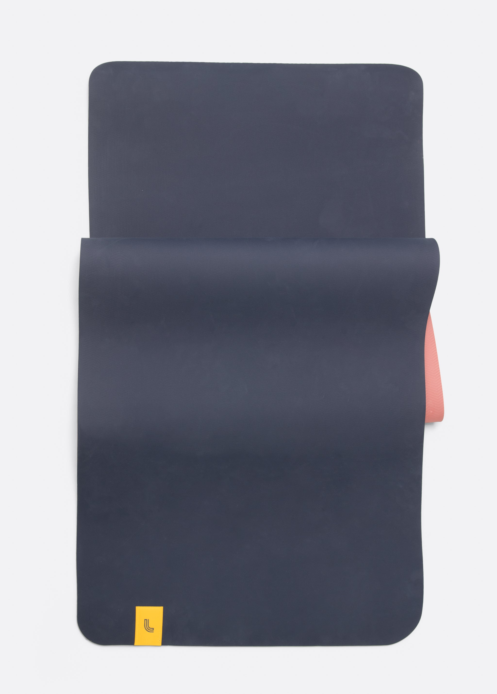 Lolë Pose yoga mat in navy, unrolled flat revealing the navy top and dusty pink underside