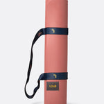Lolë Pose yoga mat in dusty pink, rolled up and secured with the navy shoulder strap