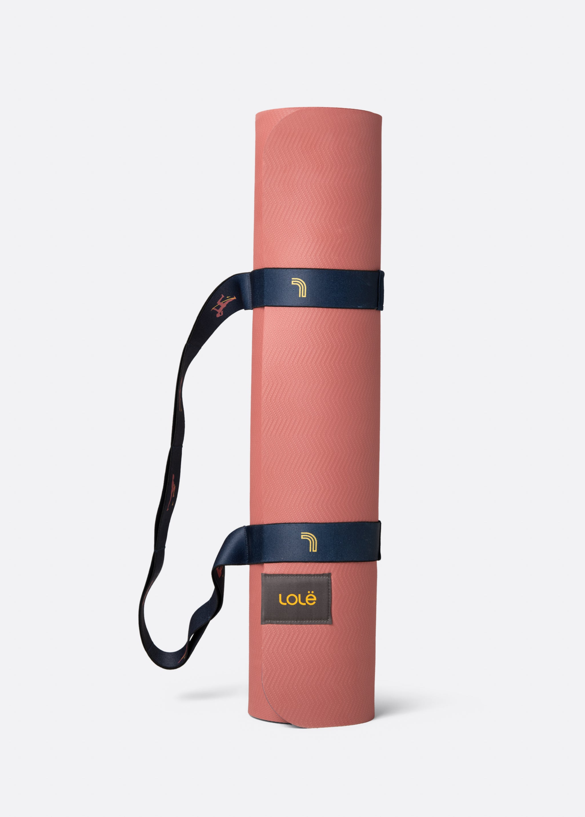 Lolë Pose yoga mat in dusty pink, rolled up and secured with the navy shoulder strap
