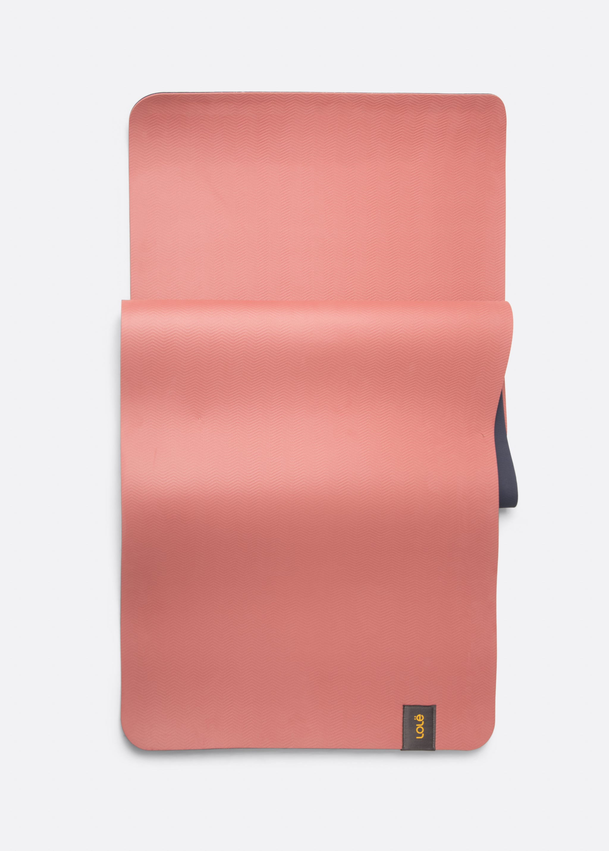 Lolë Pose yoga mat in dusty pink, laid flat showing the dusty pink top with the navy underside beneath