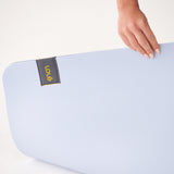 Lolë Pose yoga mat in pale blue, close-up of the ice-blue textured surface with a hand and the Lolë label
