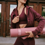 Lolë Pose yoga mat in dusty pink, carried under a woman's arm outdoors with the mauve strap