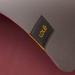 Lolë Pose yoga mat in grey, close-up of the folded edge where the grey top meets the burgundy underside