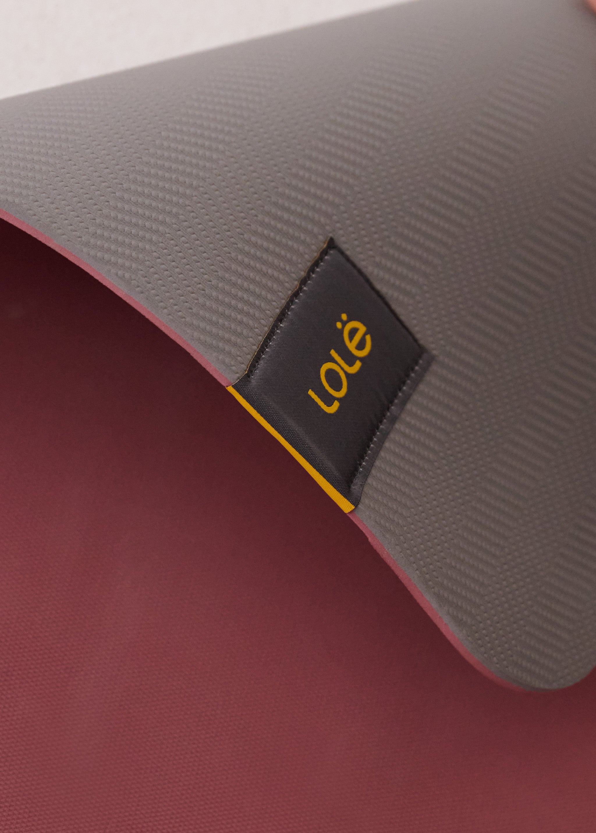 Lolë Pose yoga mat in grey, close-up of the folded edge where the grey top meets the burgundy underside