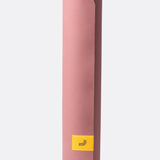 Lolë Pose yoga mat in dusty pink, rolled upright showing the dusty-pink outer surface and yellow logo tab