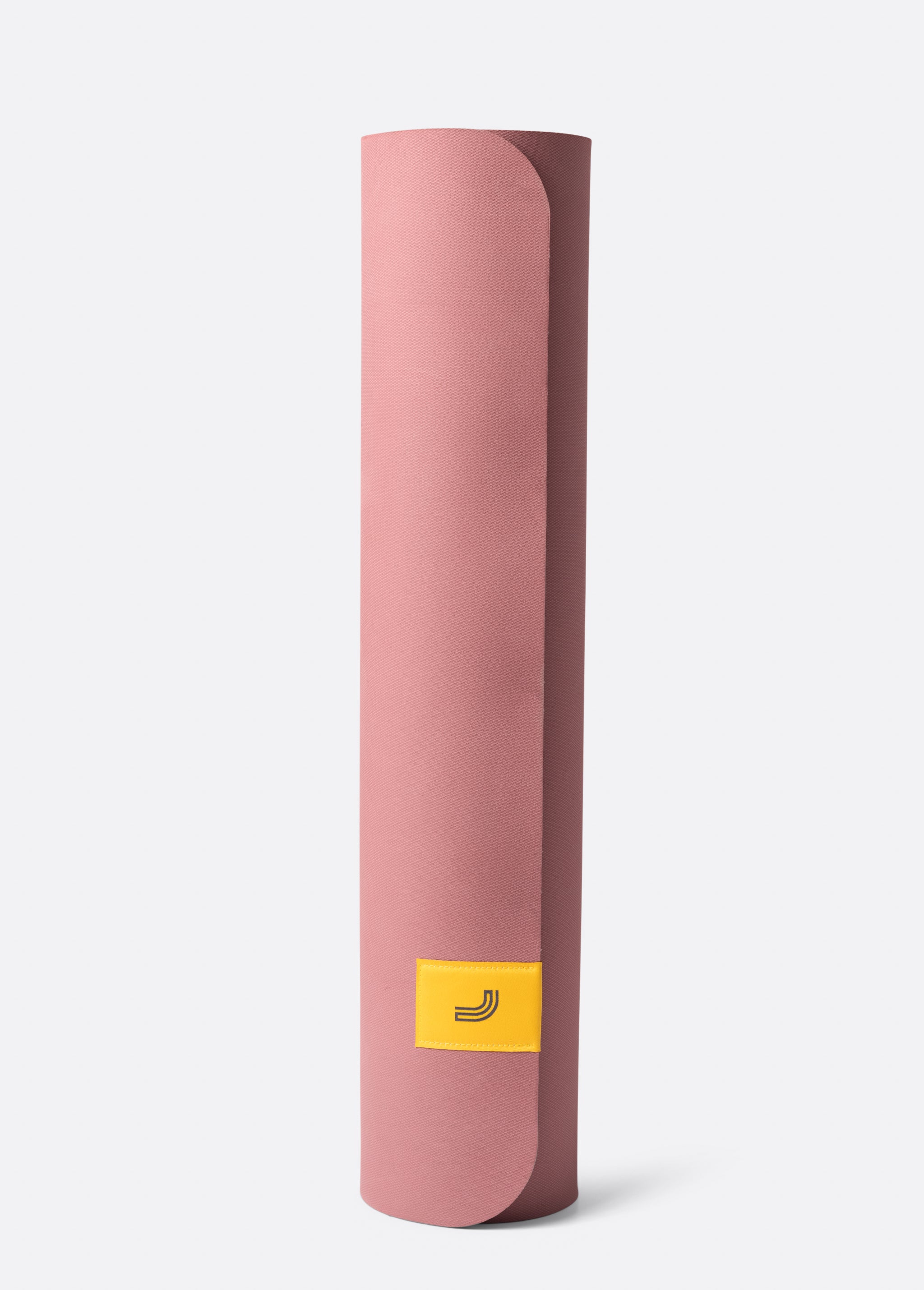 Lolë Pose yoga mat in dusty pink, rolled upright showing the dusty-pink outer surface and yellow logo tab