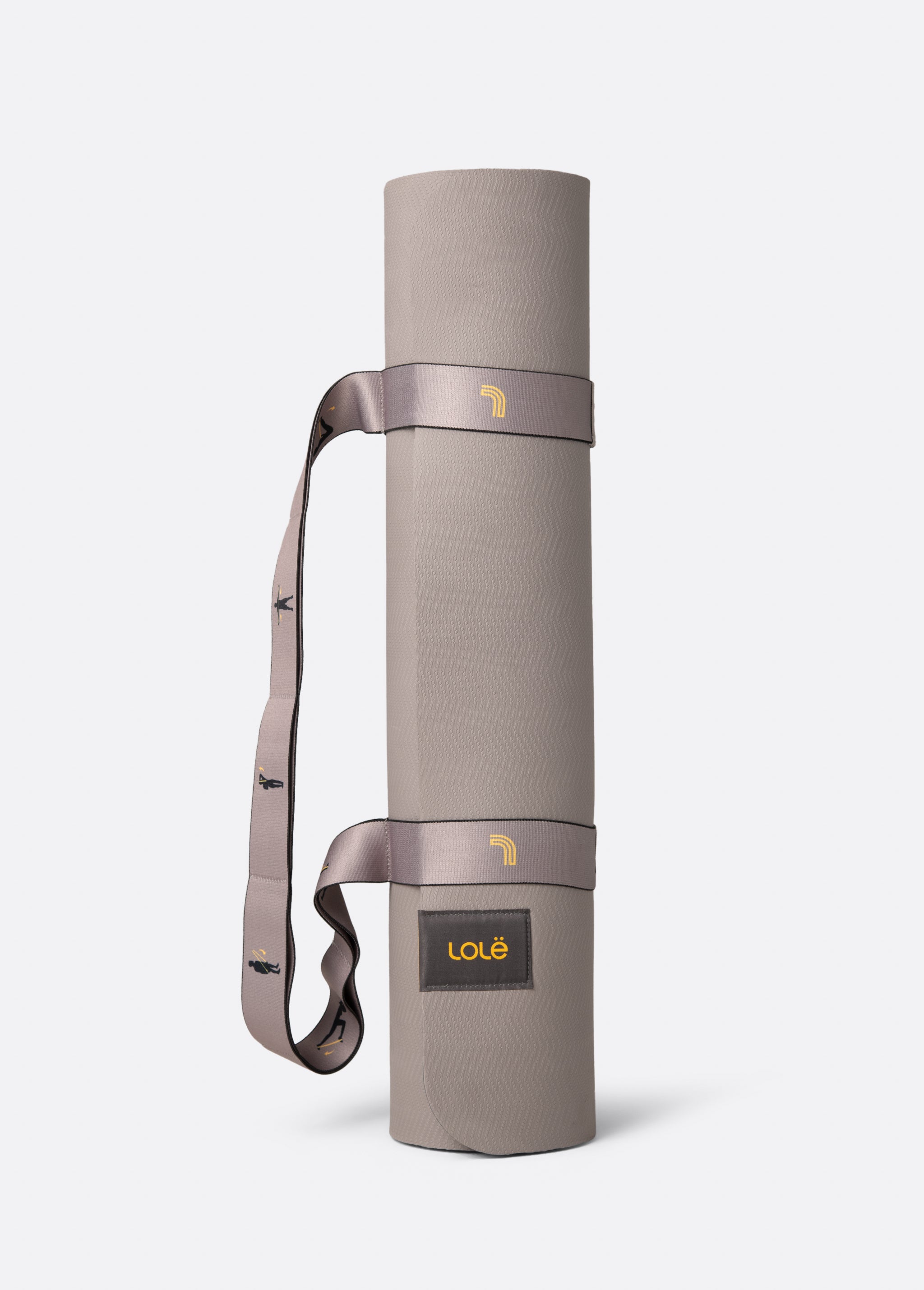 Lolë Pose yoga mat in taupe, rolled and standing upright with the taupe shoulder strap looped through