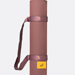 Lolë Pose yoga mat in dusty rose, rolled up with the matching shoulder strap wrapped around it