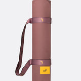 Lolë Pose yoga mat in dusty rose, rolled up with the matching shoulder strap wrapped around it