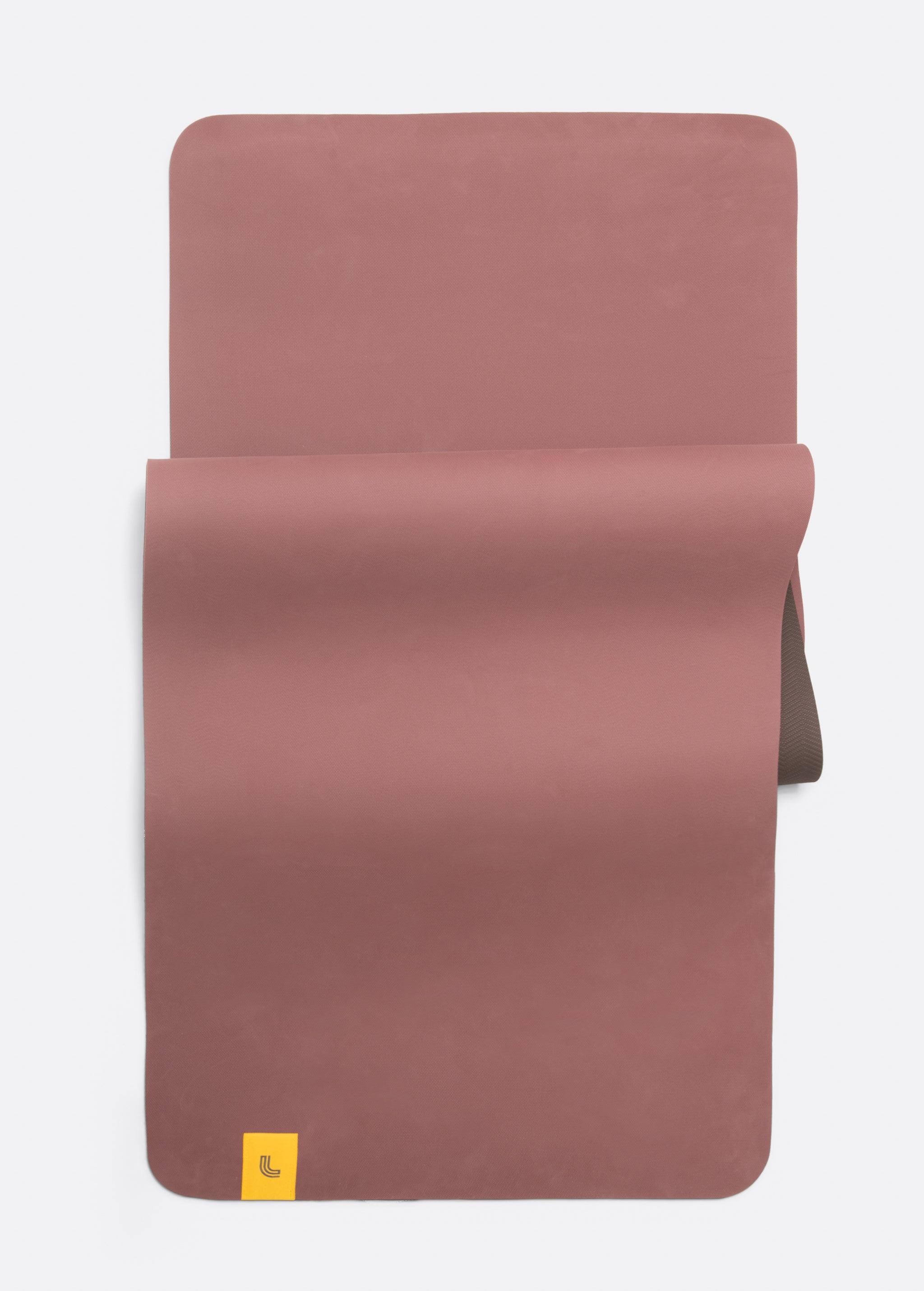 Lolë Pose yoga mat in dusty rose, unrolled flat showing the rose top with a taupe underside at the roll