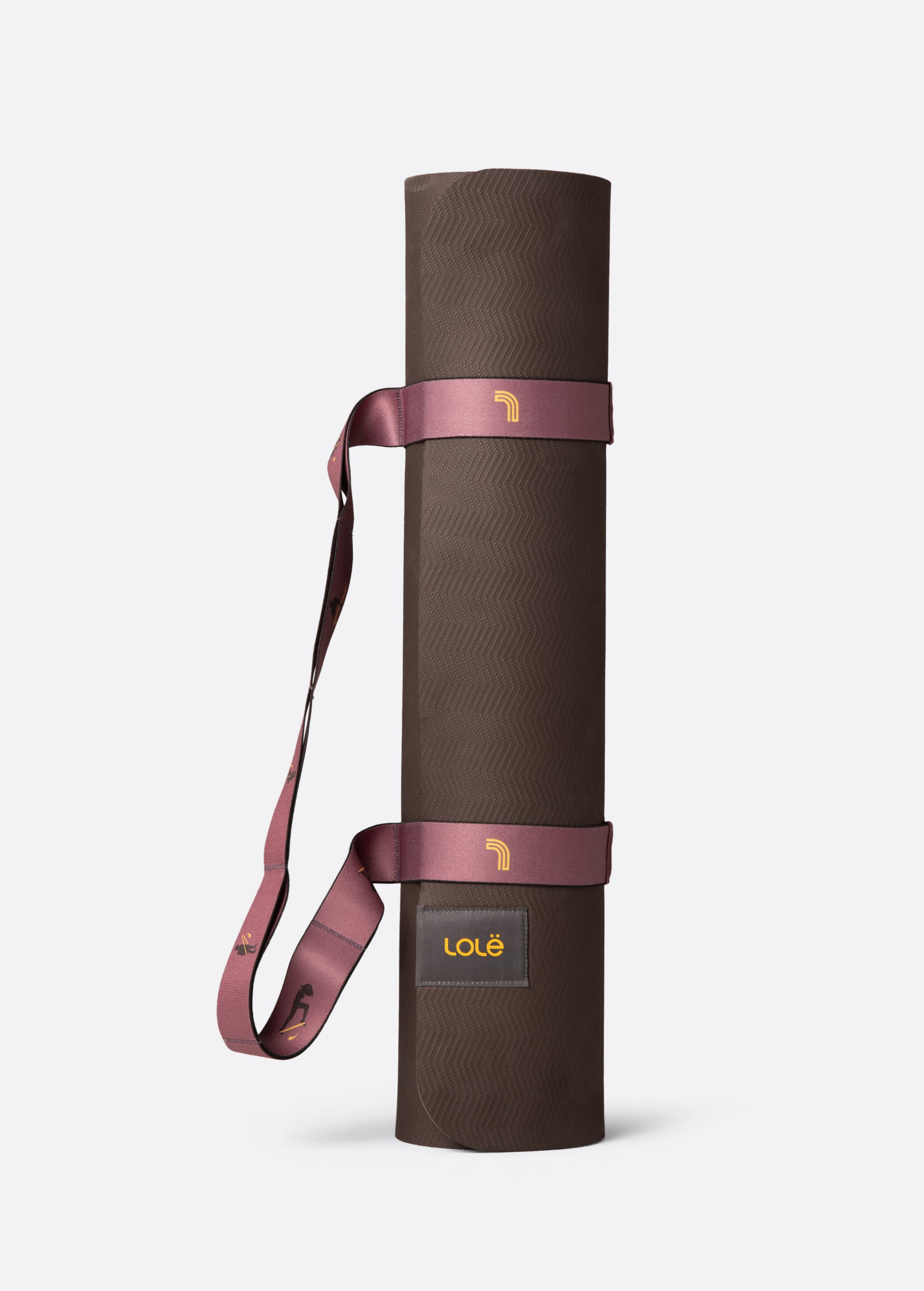 Lolë Pose yoga mat in chocolate brown, rolled and secured with the mauve carry strap