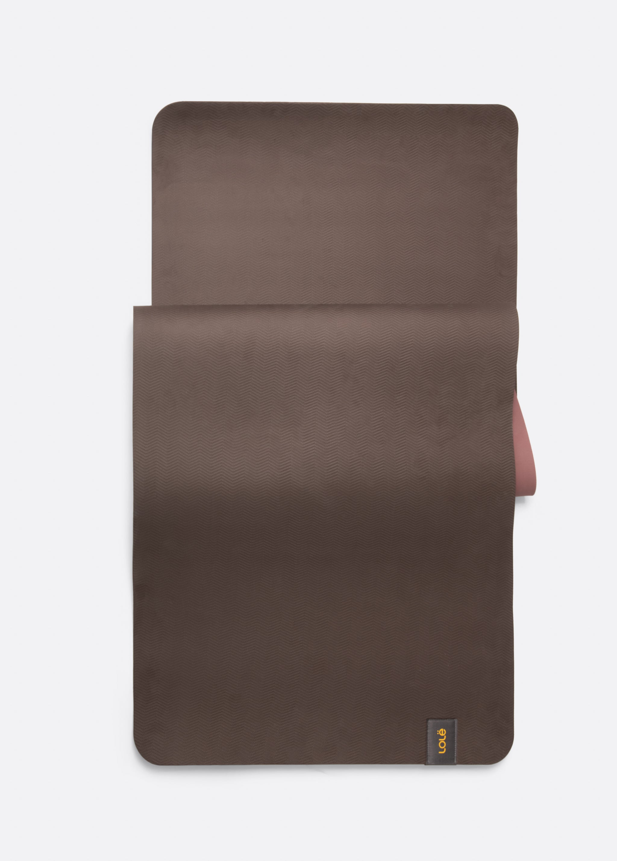 Lolë Pose yoga mat in chocolate brown, laid flat with the brown surface up and dusty rose underside at the edge
