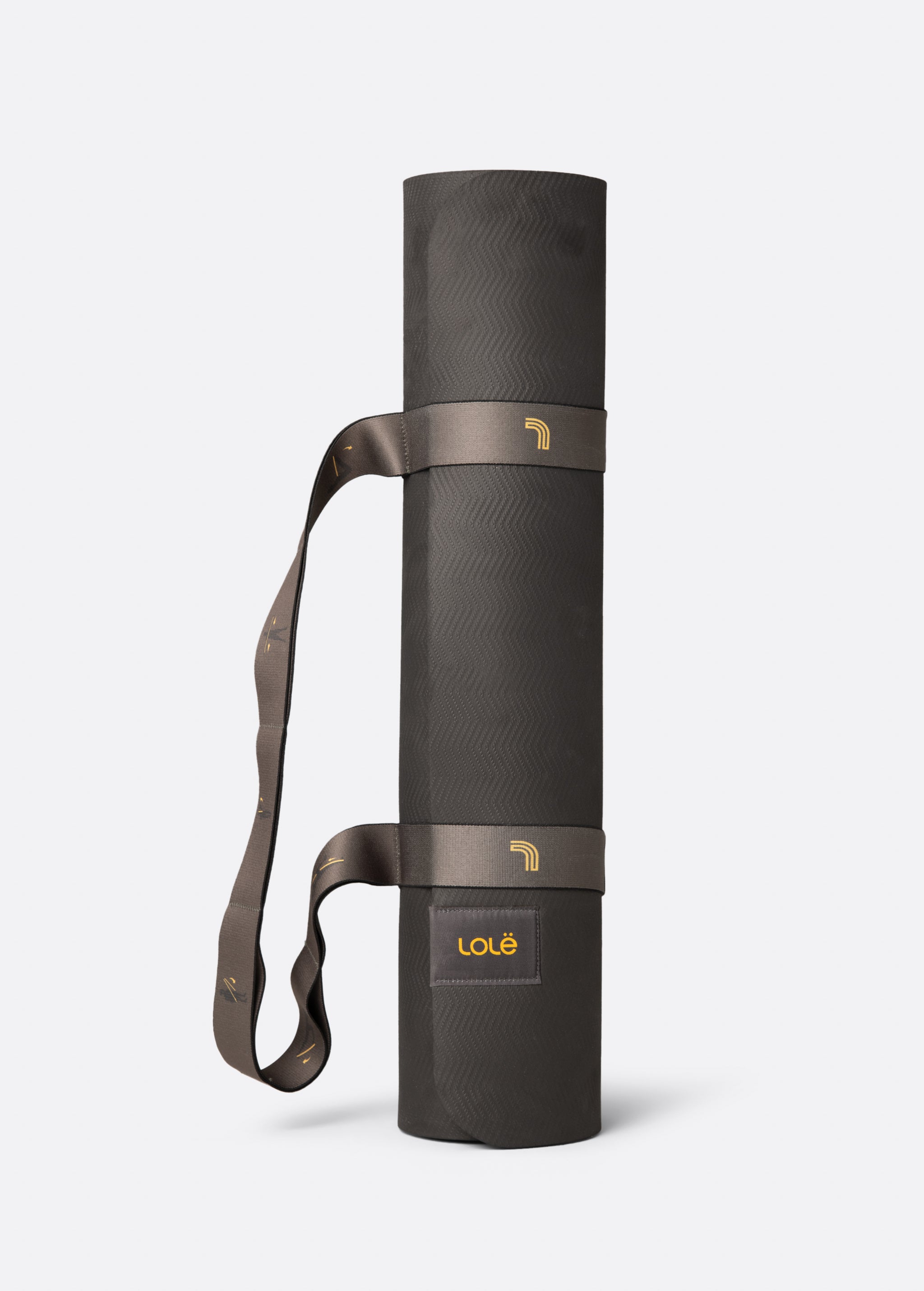 Lolë Pose yoga mat in charcoal, rolled up with the taupe shoulder strap looped for carrying
