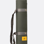 Lolë Pose yoga mat in olive green, rolled and held by the taupe strap ready to carry