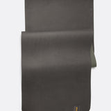 Lolë Pose yoga mat in charcoal, laid flat with charcoal surface up and olive green underside peeking underneath