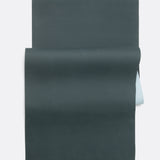 Lolë Pose yoga mat in dark teal, unrolled flat with teal top and pale ice-blue underside showing at the roll