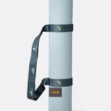Lolë Pose yoga mat in pale ice blue, rolled and secured with the dark teal carry strap