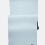 Lolë Pose yoga mat in pale ice blue, laid flat with ice-blue surface up and dark teal underside at the edge