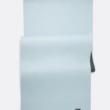 Lolë Pose yoga mat in pale ice blue, laid flat with ice-blue surface up and dark teal underside at the edge